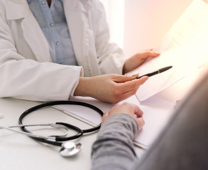 Doctor and patient are discussing about diagnosis, stethoscope and hands at the table.